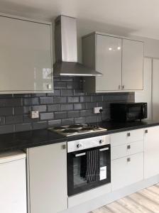 a kitchen with white cabinets and a stove top oven at Welsh Getaway Home No 1 - 10 mins to Bike Park Wales in Merthyr Tydfil