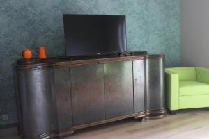 TV en la parte superior de un armario de madera con silla verde en Landperle Darze, en Altenhof