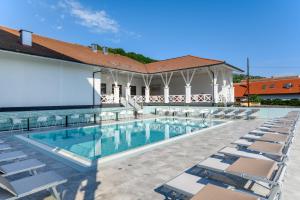 a swimming pool with chairs and a building at Mercure Tokaj Center in Tokaj