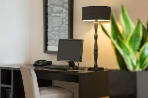 a desk with a computer and a lamp on it at Hotel Dom Goncalo & Spa in Fátima