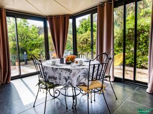 a dining room table with chairs and a table and windows at Le Clos des Eucalyptus in Plan-de-la-Tour