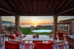 a patio with a table and chairs and a pool at Due Lune Puntaldia Resort & Golf in San Teodoro