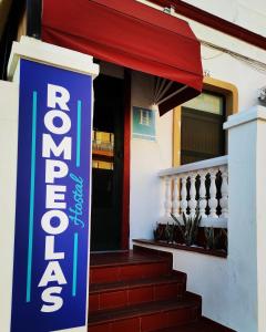 a sign in front of a building with a red awning at Rompeolas Playa in Chipiona