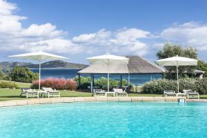 a swimming pool with two umbrellas and chairs at Due Lune Puntaldia Resort & Golf in San Teodoro