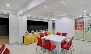 a meeting room with a white table and red chairs at Treebo Grand Town House in Faridabad