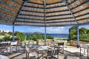 a large wooden pavilion with tables and chairs and the ocean at Due Lune Puntaldia Resort & Golf in San Teodoro