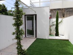 uma porta aberta numa casa branca com um relvado verde em Station House em Guimarães