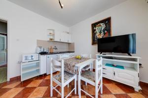 cocina con mesa con sillas y TV en Olive Garden Apartments, en Sveti Stefan