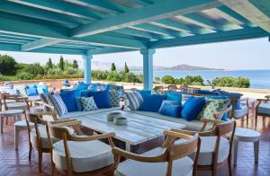 a table and chairs on a patio with the ocean in the background at Due Lune Puntaldia Resort & Golf in San Teodoro