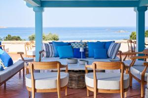 a patio with a couch and chairs and the ocean at Due Lune Puntaldia Resort & Golf in San Teodoro