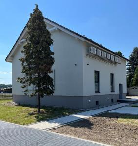 a white house with a tree in front of it at Fotel Mikołowska in Tychy