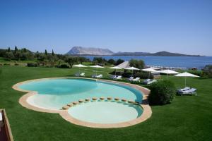a large swimming pool with chairs and umbrellas at Due Lune Puntaldia Resort & Golf in San Teodoro