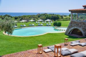 a swimming pool in a yard with chairs and a fireplace at Due Lune Puntaldia Resort & Golf in San Teodoro