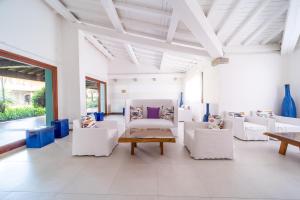 a white living room with white chairs and tables at Due Lune Puntaldia Resort & Golf in San Teodoro