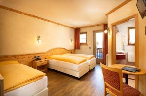 a hotel room with two beds and a table at Hotel La Pastorella in Livigno