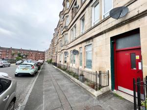 a red door on a building with cars parked on a street at 1 Bedroom Glasgow Apartment in Glasgow