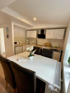 une cuisine avec une table et des chaises et une cuisine avec des armoires blanches dans l'établissement Ferienwohnung Wasserkunst, à Bad Harzburg