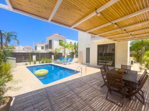 a patio with a table and chairs and a swimming pool at Fotini Villas in Protaras