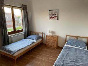 2 camas individuales en una habitación con ventana en Apartamenty Łeba, en Łeba