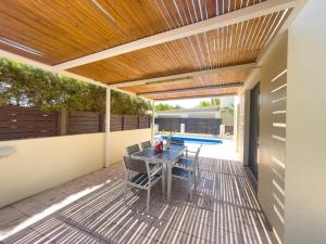 um pátio com uma mesa e cadeiras sob um tecto de madeira em Fotini Villas em Protaras