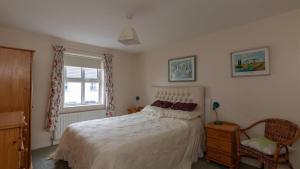 een slaapkamer met een bed, een raam en een stoel bij Strand Cottages Ballycastle Seafront in Ballycastle