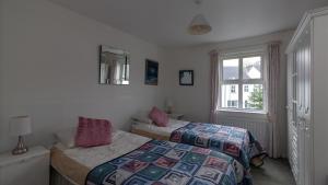 een slaapkamer met 2 bedden en een raam bij Strand Cottages Ballycastle Seafront in Ballycastle