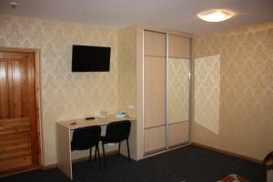 a room with a desk with two chairs and a television at Balvi Hotel in Balvi
