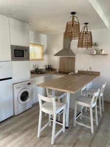 a kitchen with a wooden table and white chairs at Relax y sol in Torreguadiaro