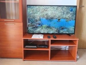 a flat screen tv on a wooden entertainment center at Apartment Ashton Hall - Sonnenstrand – Ost in Sunny Beach