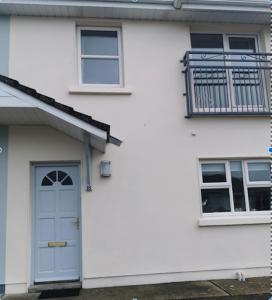 a white house with a blue door and a balcony at Lios NaMara in Lahinch