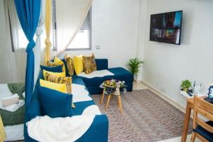 een woonkamer met een blauwe bank en gele kussens bij Studio Cozy Parc Mohammedia in Mohammedia