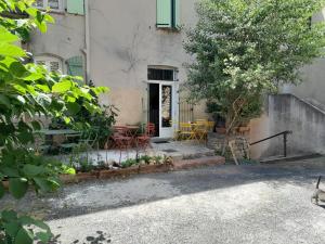 a house with chairs and a tree in front of it at LE PRIEURE in Saint-Florent-sur-Auzonnet