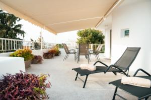 a patio with chairs and a table on a balcony at Vouliagmeni Stylish Homes by BluPine in Athens +56 photos