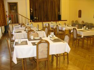 a dining room with tables and chairs with white table cloth at Hotel Alga in Ustka