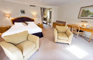 a bedroom with a bed and two chairs and a desk at Penmere Manor Hotel in Falmouth