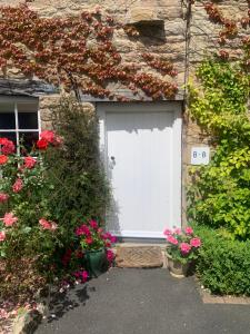 una porta bianca in garage su un edificio in pietra con fiori di Dalton House Bed and Breakfast a Newcastle upon Tyne
