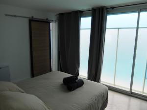 a black bag sitting on a bed in a room with windows at Superbe appartement proche des plages avec parking gratuit in Ramatuelle
