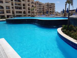 einem Pool mit blauem Wasser vor einem Gebäude in der Unterkunft Aldau heights in Hurghada