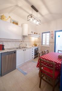 a kitchen with white cabinets and a table with a red table cloth at Casa da Travessa - Óbidos in Óbidos