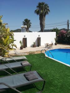 un patio trasero con piscina y césped verde en CASA ENTERA SA CALETA!! en San Jose de sa Talaia