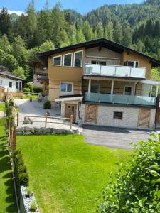 una casa con un césped verde delante de ella en Ferienwohnung Wildkogelblick, en Bramberg am Wildkogel