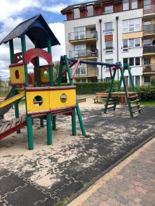 a playground with a slide and a swing at Cozy apartment close to Gdansk & Airport in Gdańsk