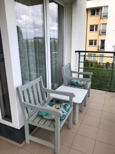 zwei weiße Stühle auf einem Balkon neben einem Fenster in der Unterkunft Cozy apartment close to Gdansk & Airport in Danzig