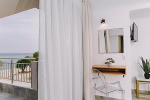 - un rideau blanc dans une chambre avec une chaise et un balcon dans l'établissement BLUE STONE Luxury Suites, à Limenaria