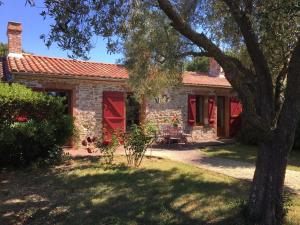 a stone house with red doors and a tree at LE CLOS DE LA VINIERE in Jard-sur-Mer