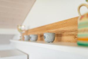 a shelf with a row of mugs on it at Aparthotel-Almgasthaus Gemsli - A bisal Österreich überm Schweizer Rheintal in Sevelen