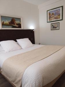 a bedroom with a large white bed with two pillows at Logis Drom'sud Hotel in Donzère