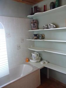 een badkamer met een bad, een wastafel en planken bij Chambre indépendante deux personnes au bord de la Blanche in Selonnet