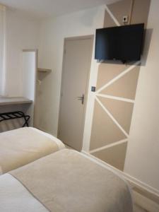 a bedroom with two beds and a door with a television at Logis Drom'sud Hotel in Donzère