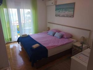 a bedroom with a large bed with pink and blue pillows at Guesthouse Villa Stanger in Lovran